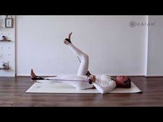 a woman is doing yoga on a mat with her arms in the air and one leg up