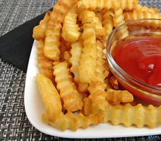 a white plate topped with waffle fries and ketchup