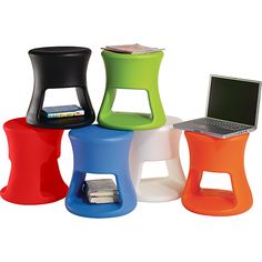 four different colored stools with a laptop on one side and a stack of books on the other