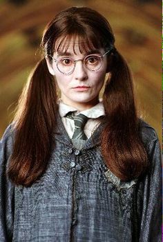 a woman with long hair wearing glasses and a harry potter outfit is looking at the camera