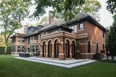 a large brick house sitting on top of a lush green field