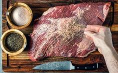 a person is cutting up a steak on a cutting board with spices and seasonings