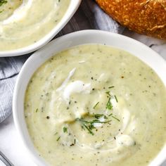 two white bowls filled with soup next to bread