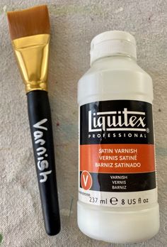 a paintbrush next to a bottle of varnishing paste and a golden brush