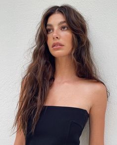 a woman with long brown hair wearing a black top