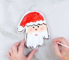 someone is painting a paper santa clause on a piece of white marble with red paint