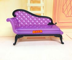 a purple toy couch sitting on top of a white floor next to a pink wall