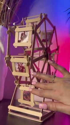 a woman's hand is placing pictures on a ferris wheel