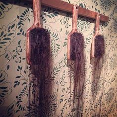 there are three hair brushes hanging from the hooks on the wall next to each other