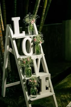 a white ladder with flowers on it and the word love spelled out in large letters