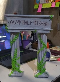 a laptop computer sitting on top of a desk next to a sign that says kamp half blood