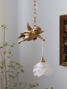 a golden bird is hanging from a chandelier in a room with white walls