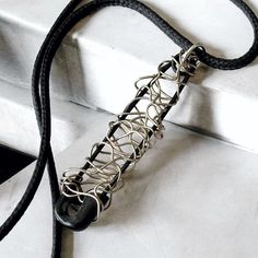 a black and silver necklace on a white surface