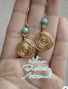 a pair of gold spiral earrings with turquoise beads on the end of each dangle