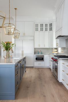 a large kitchen with white cabinets and blue island counter tops, gold accents on the doors