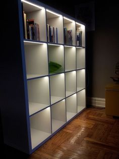 an illuminated bookcase in the corner of a room