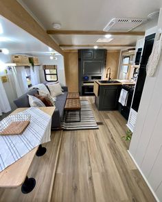 a living room and kitchen area in a mobile home with wood flooring on the walls