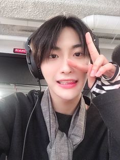 a young man wearing headphones making the peace sign with his hand while sitting in front of him