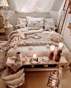 a bed with blankets, pillows and candles on it in a room filled with lights