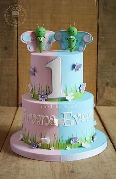 a three tiered cake decorated with green and blue decorations on top of a wooden table