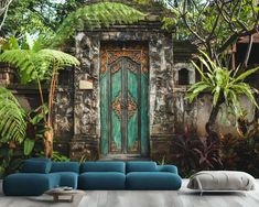 a living room with a blue couch and green door in the middle of it, surrounded by greenery