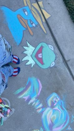 a child is standing on the sidewalk with chalk crayons