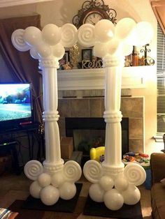 an arch made out of balloons in front of a fireplace with a television on it