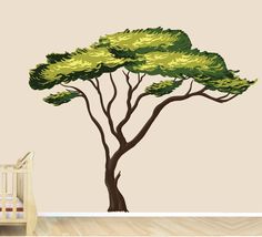 a baby's room with a crib and wall decal featuring a tree