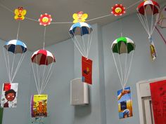 several colorful kites hanging from the ceiling in a room with blue walls and posters on the wall