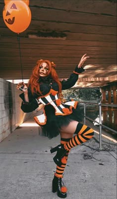 a woman dressed up as a witch holding an orange balloon