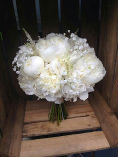 a bouquet of white flowers sitting on top of a wooden chair