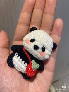 a small crocheted panda bear sitting on someone's hand