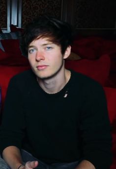 a young man sitting on top of a red couch