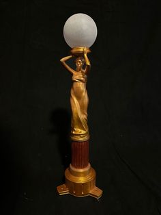 a golden statue holding a white ball on top of it's head