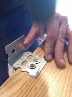 a person is using a pair of scissors to cut the edge of a piece of wood