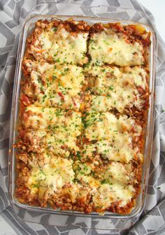 a casserole dish with meat, cheese and sauce in it on a patterned cloth