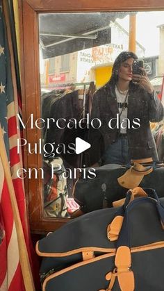 a woman taking a photo in front of a mirror with luggage on the ground and an american flag behind her