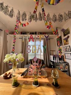 a table with wine glasses, plates and vases on it in front of a window