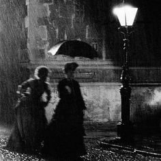 two women are standing under an umbrella in the rain