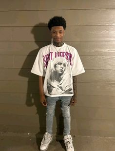 a young man standing in front of a wall wearing a t - shirt with the image of marilyn monroe on it