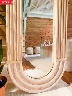 a large mirror sitting on top of a wooden floor next to a potted plant