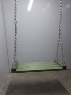 a green wooden swing hanging from a ceiling