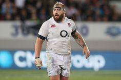 a rugby player is standing on the field with his hand in his pocket and looking at the ground