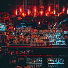 a bar with lots of bottles and lights hanging from the ceiling