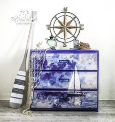 a blue dresser with a sailboat painted on the front and bottom, along with other items