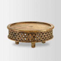 a round wooden tray with holes in the middle and an intricate design on it's sides