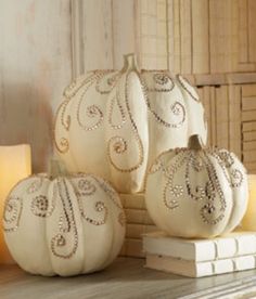 three white pumpkins sitting on top of a wooden table next to candles and books