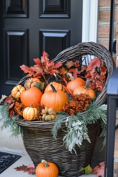 a basket filled with lots of pumpkins and greenery