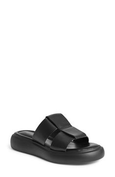 Oversized leather straps kick off a modern slide sandal set atop lightweight padding and a chunky contrast sole. 1 1/2" platform Flat sole Cushioned footbed Leather upper and lining/synthetic sole Imported Black Leather Footbed Platform Slide Slippers, Black Leather Slide Platform Slippers, Modern Platform Slippers With Leather Footbed For Beach, Modern Platform Slippers With Textured Sole For Beach, Modern Black Platform Footbed Sandals, Modern Sport Sandals With Leather Footbed, Modern Black Sport Sandals With Leather Footbed, Modern Synthetic Sport Sandals With Leather Footbed, Modern Black Leather Footbed Sandals