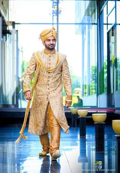 a man in a golden outfit walking down the runway